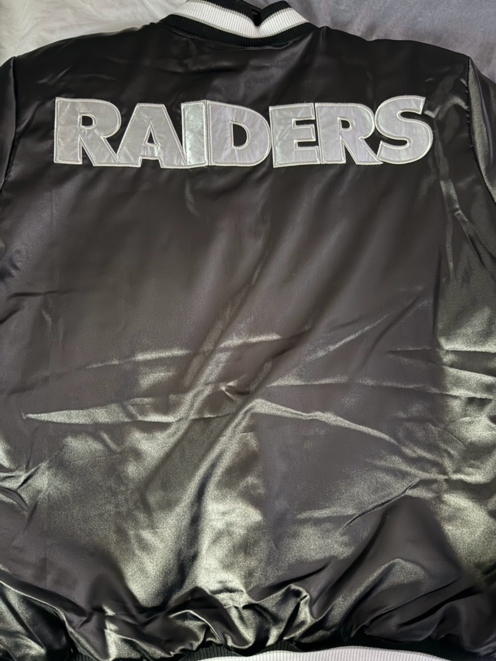 Black Raiders Satin Bomber Jacket with Silver Lettering women’s size large